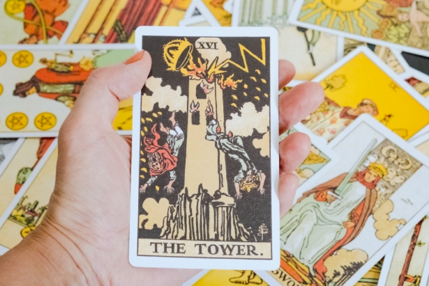 手持高塔塔羅牌的近拍圖，象徵突發變動與重建力量的占卜解讀畫面