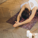 一位中年女性閉著眼睛，在明亮的客廳中進行伸展靜坐，雙手高舉過頭，表情平靜放鬆