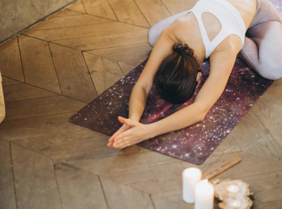 一位中年女性閉著眼睛，在明亮的客廳中進行伸展靜坐，雙手高舉過頭，表情平靜放鬆