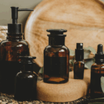 一系列深棕色精油瓶，擺在木紋圓盤和編織墊前，周圍裝飾有綠色尤加利葉