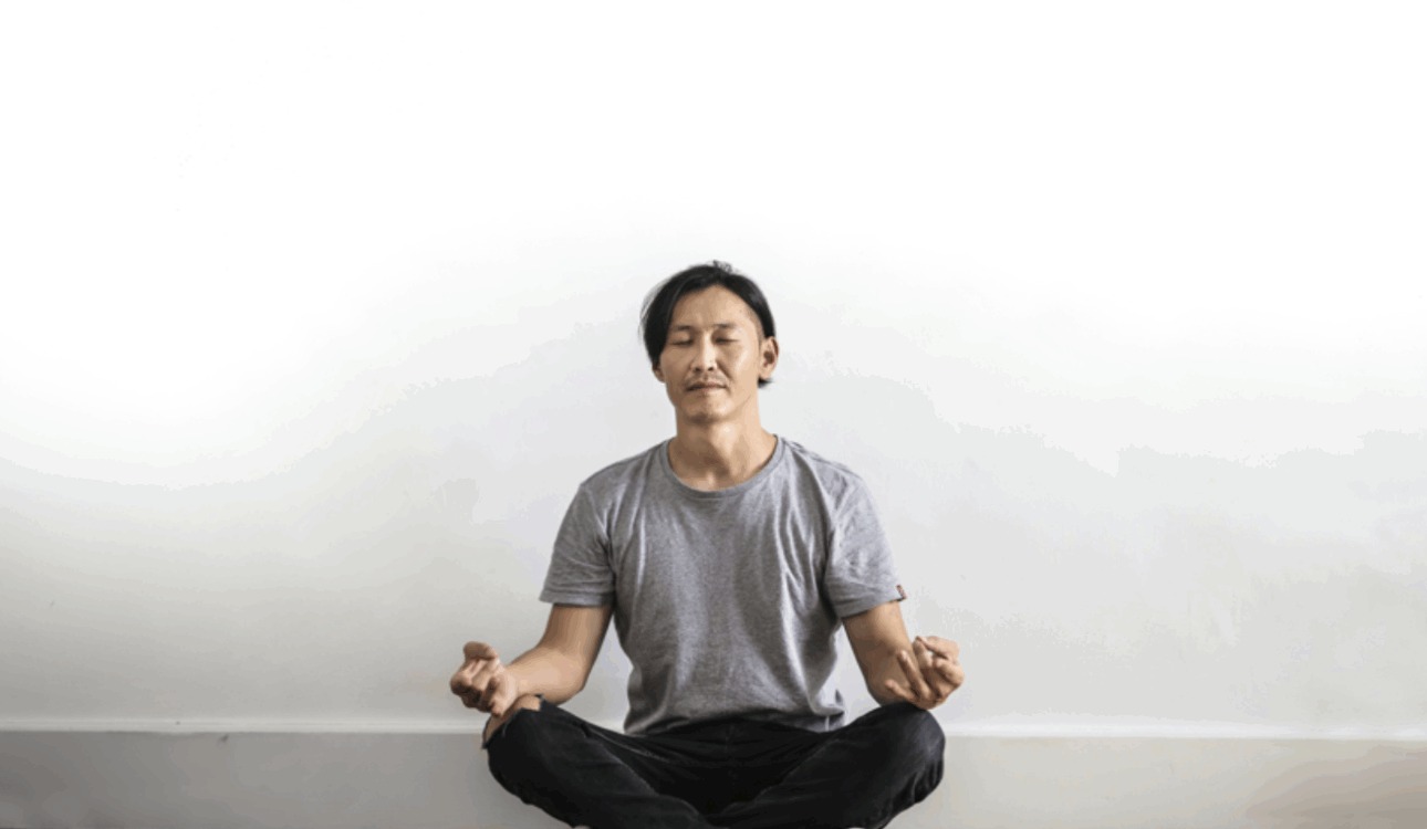 男子在白色牆壁前盤腿冥想/瑜珈和靜坐練習/專注平靜放鬆的冥想姿勢/提升專注力與緩解壓力