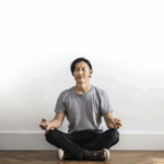 男子在白色牆壁前盤腿冥想/瑜珈和靜坐練習/專注平靜放鬆的冥想姿勢/提升專注力與緩解壓力