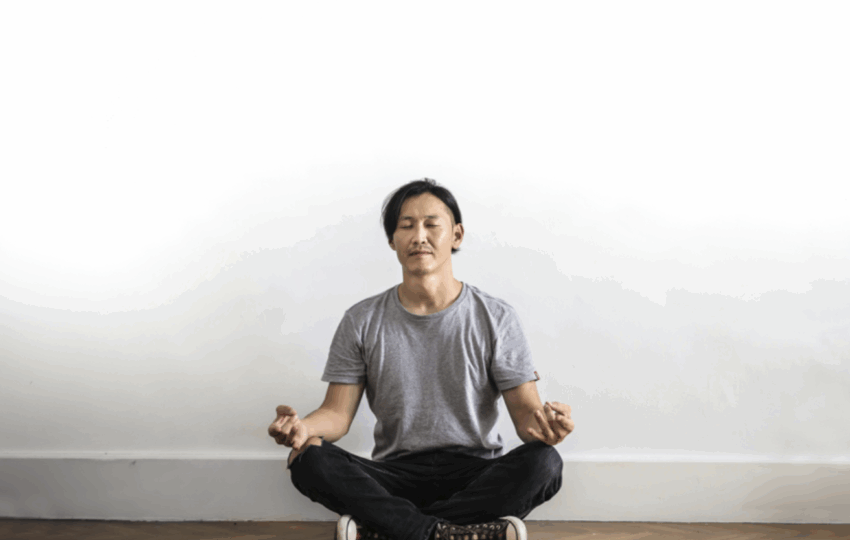 男子在白色牆壁前盤腿冥想/瑜珈和靜坐練習/專注平靜放鬆的冥想姿勢/提升專注力與緩解壓力