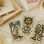 木質桌面上擺放著三張塔羅牌，分別是「世界」（The World）、「太陽」（The Sun）與「聖杯二」（2 of Cups），旁邊還有乾燥花束、水晶原石、一疊牌卡以及一個點燃黃色花朵蠟燭的香氛座。