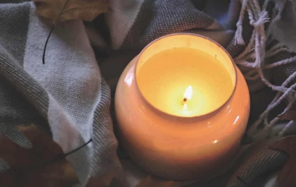 柔軟織品間點燃的燭光近拍畫面，溫暖火焰映出安定、療癒的靜謐感