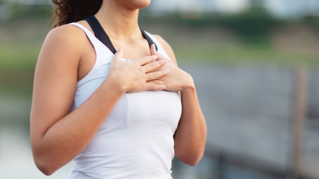 女性練習冥想呼吸法，雙手交疊於胸前感受心跳，專注於自我療癒