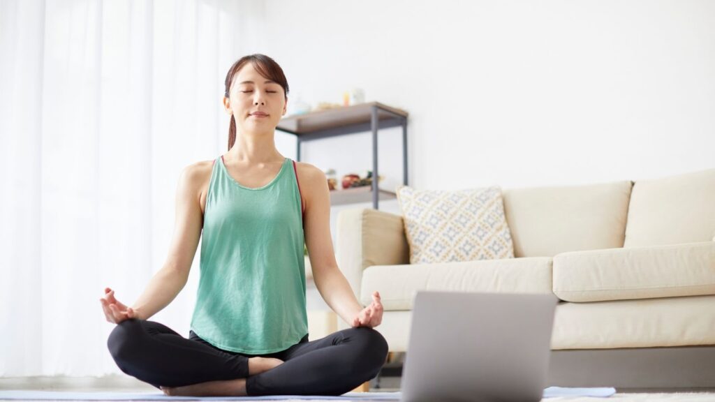 居家練習線上瑜珈課程，透過筆電視訊跟隨老師進行正念冥想
