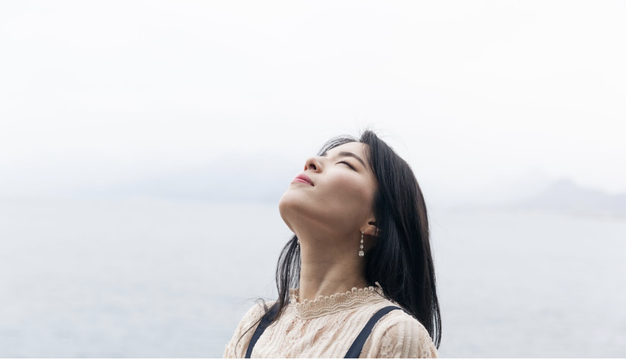 一位女性在戶外閉目感受自然的呼吸，象徵心靈平靜與釋放壓力