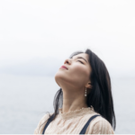 一位女性在戶外閉目感受自然的呼吸，象徵心靈平靜與釋放壓力