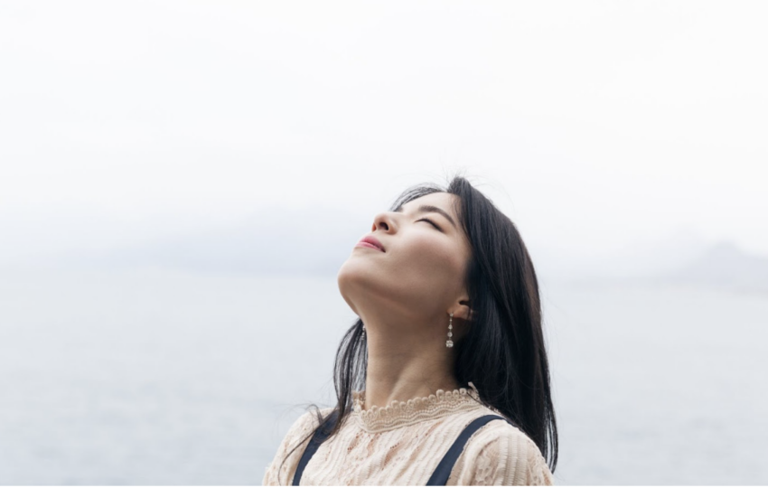 一位女性在戶外閉目感受自然的呼吸，象徵心靈平靜與釋放壓力