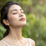 一名年輕女性在戶外綠意盎然的背景下閉目養神，微風吹拂，呈現出與大自然連結的寧靜感