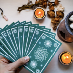 一隻手拿著一疊綠色曼陀羅圖案的塔羅牌呈扇形展開，背景有蠟燭、粉晶與擴香石，營造神祕氛圍