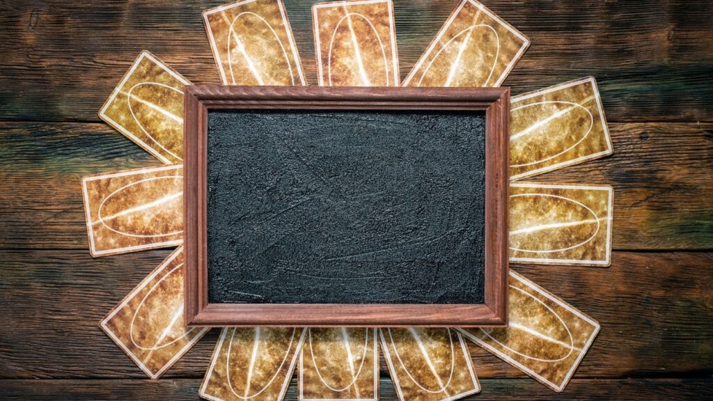  木質桌面上的塔羅牌陣，中央放置一個空白黑色畫框，適合用於展示神祕學相關訊息或標題空間。