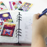 塔羅牌占卜師在筆記本上記錄占卜結果與星盤分析] 敘述： 塔羅牌陣與手寫筆記的交織，是與潛意識對話的過程。透過詳細的記錄，將神祕學符號轉化為生活指引