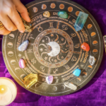 俯瞰圓形占星盤，上面放有多種彩色水晶柱和拋光寶石，一隻戴著戒指的手正在擺放水晶