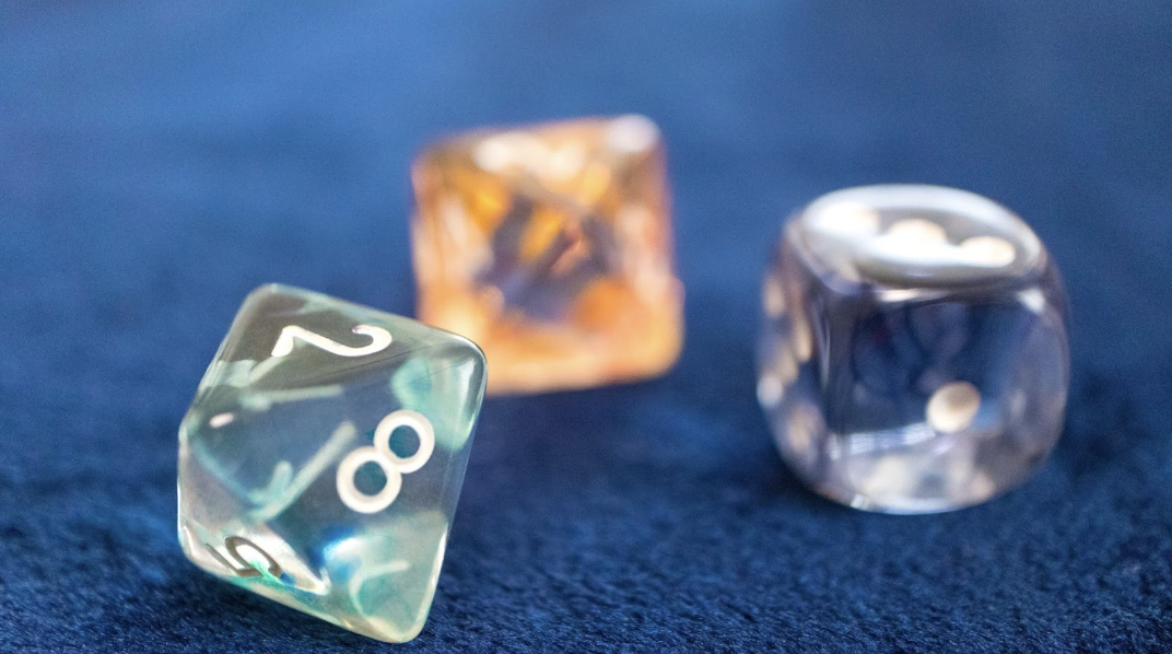 藍色絲絨背景上散落著三顆半透明且帶有光澤的占卜骰子，前景骰子清晰呈現數字 2、8、5，背景骰子則帶有柔和的橘色與紫色調